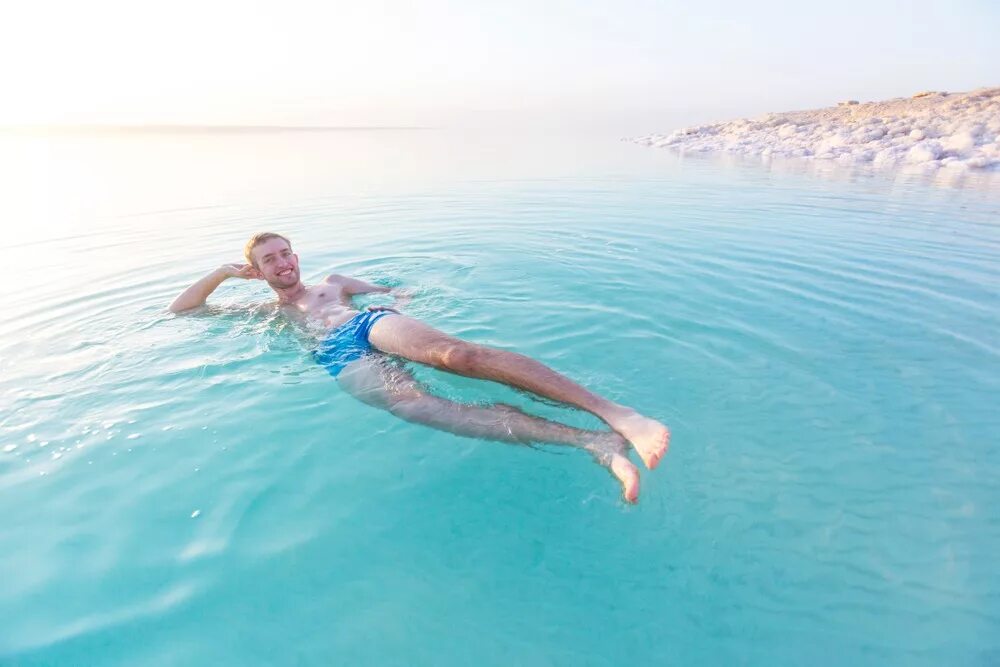 Мертвое море человек на воде. Мертвое море плавать. Мертвое море люди. Мертвое море купание. Человек лежит в воде.