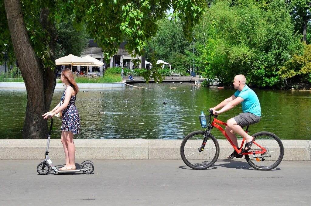 Человек на велосипеде в парке. Самокат велосипед. Велосипедист в парке. Люди в парке на самокатах.
