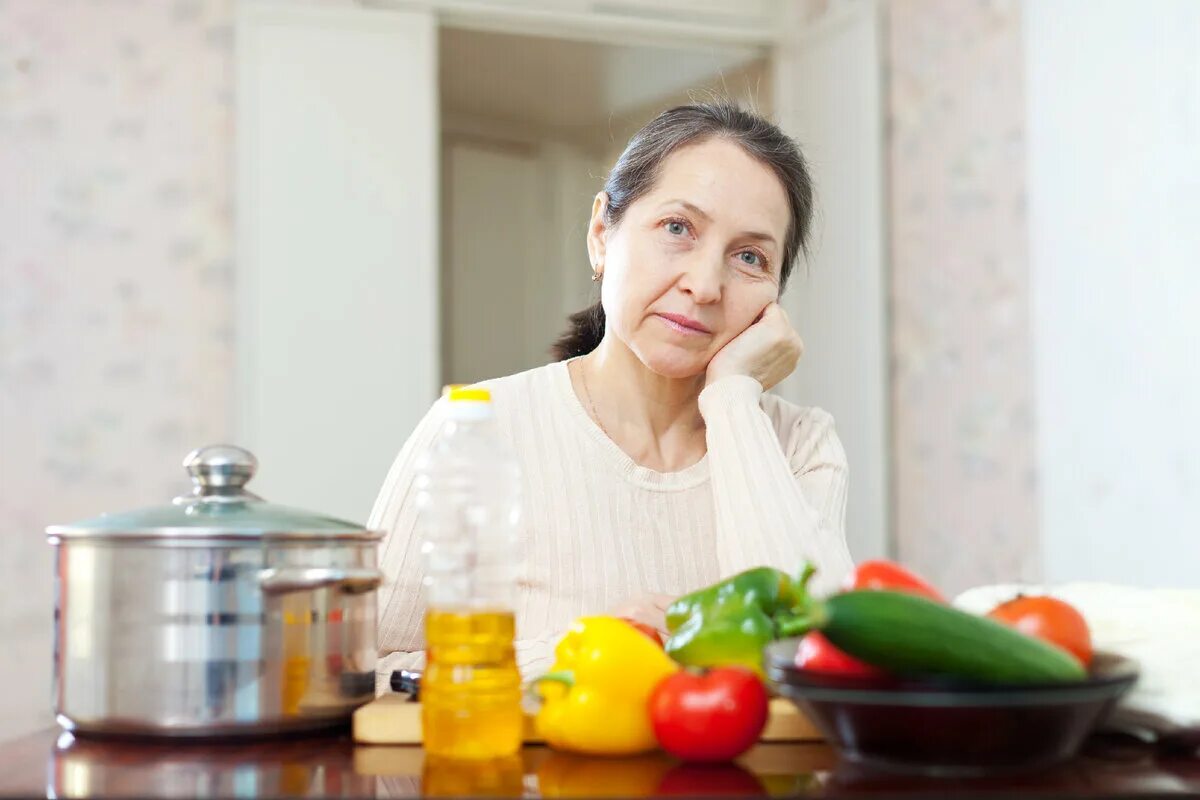 Пожилая женщина на кухне. Хозяйка с рыбой. Мама на кухне. Женщина готовит рыбу. Бабушка на кухне.