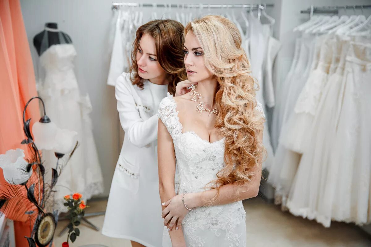Девушка продает платье. Примерка свадебного платья. Девушка в свадебном салоне. Невеста примеряет свадебное платье. Фотосессия в свадебном салоне.