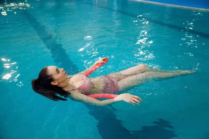 Женщина плавает в бассейне. Беременные в бассейне животы. Пузо в бассейне.