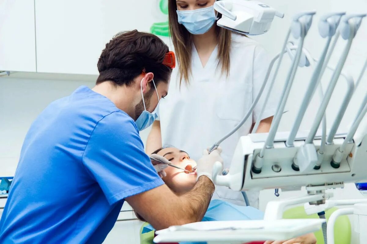Три стоматолога. Фотографии стоматологии. Стоматологические процедуры. Стоматолог лечит зубы.