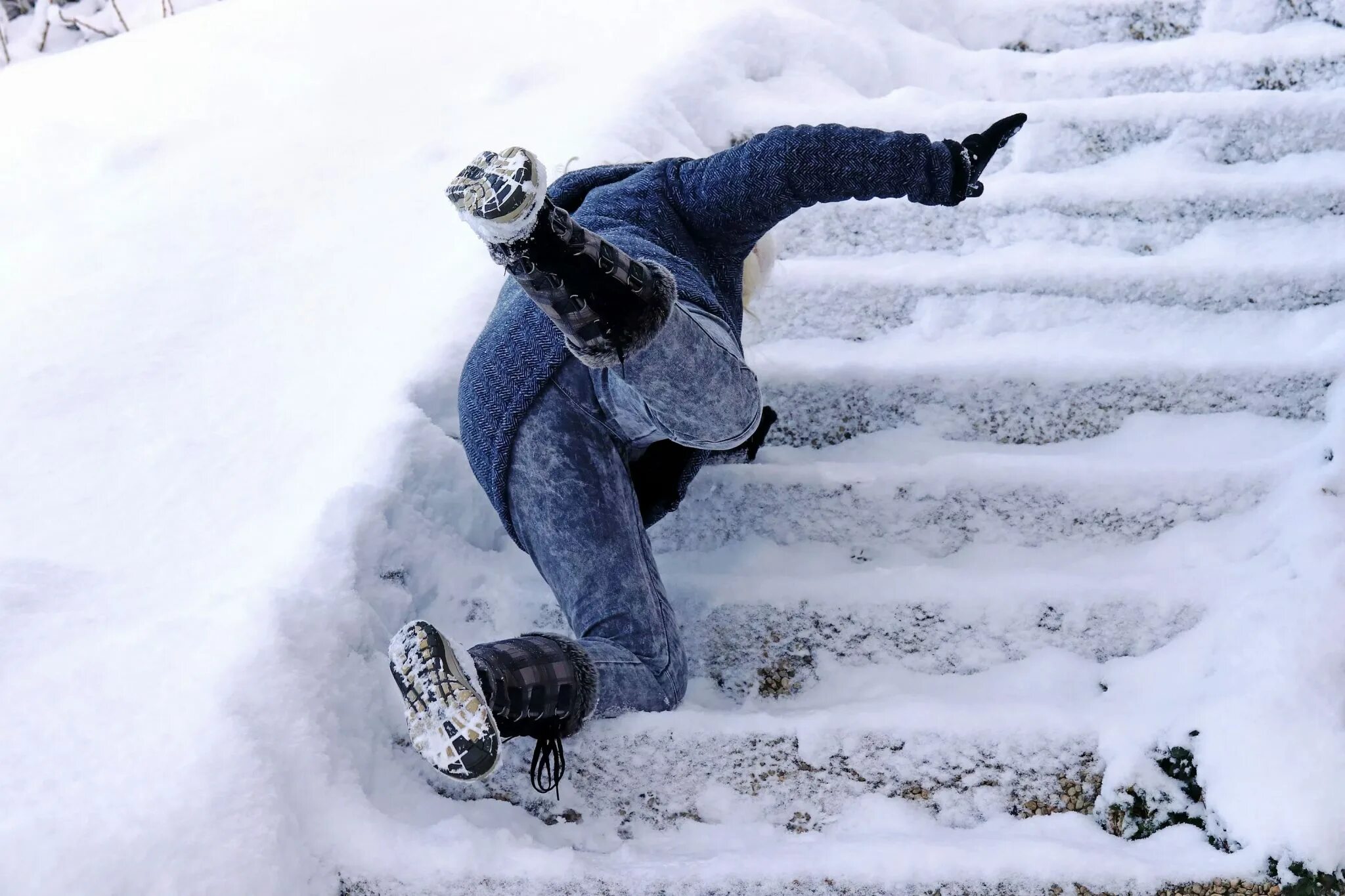 Он поскользнулся поднимаясь по лестнице. Скользкая лестница зимой. Человек падает на льду. Люди зимой.