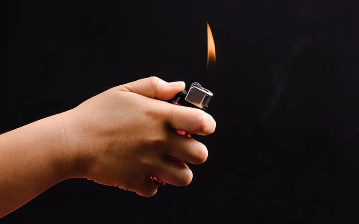 Поджигание спички. Зажигалка с огнем. Поджог. Рука со спичкой. Пламя зажигалки.