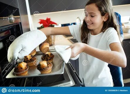 Cute Girl Baking Chocolate Muffins in the Oven with Her Family in the.