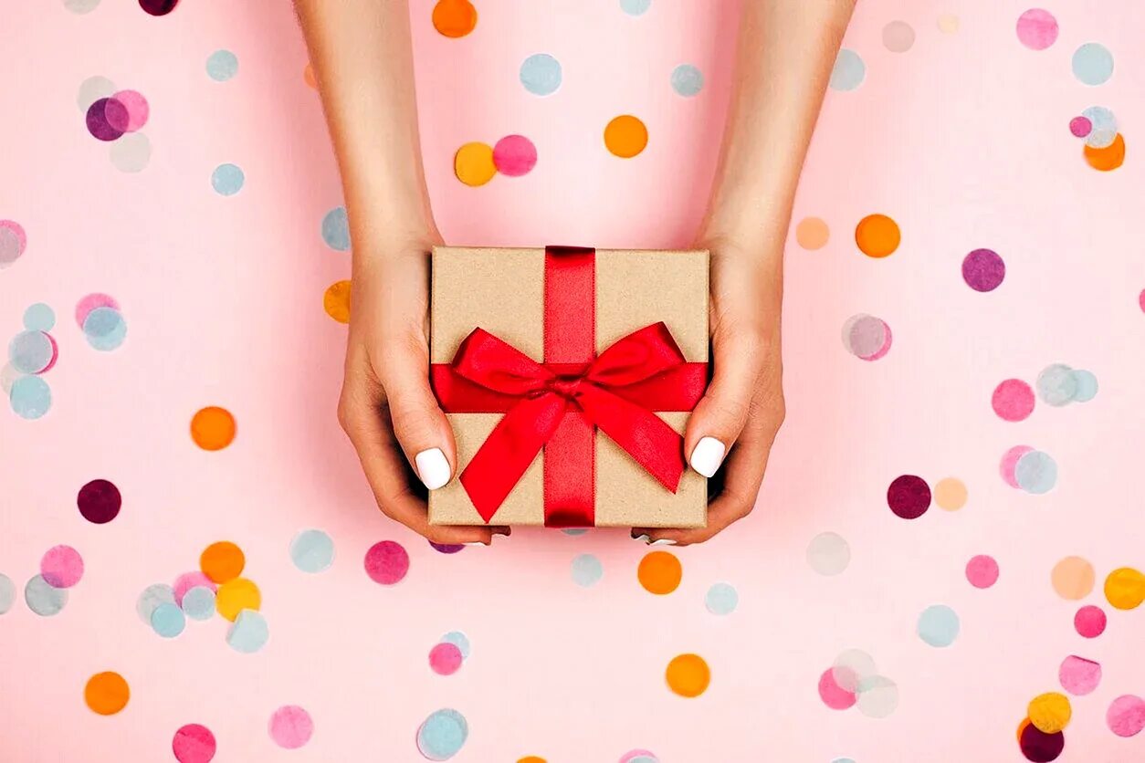 Увидеть сюрприз. Яркий подарок. Подарок в руках. Подарок на розовом фоне. Стильный подарок.