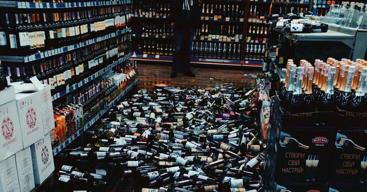 Разбитое вино. Разбитые бутылки в магазине. Стеллаж с бутылками вина в магазине.
