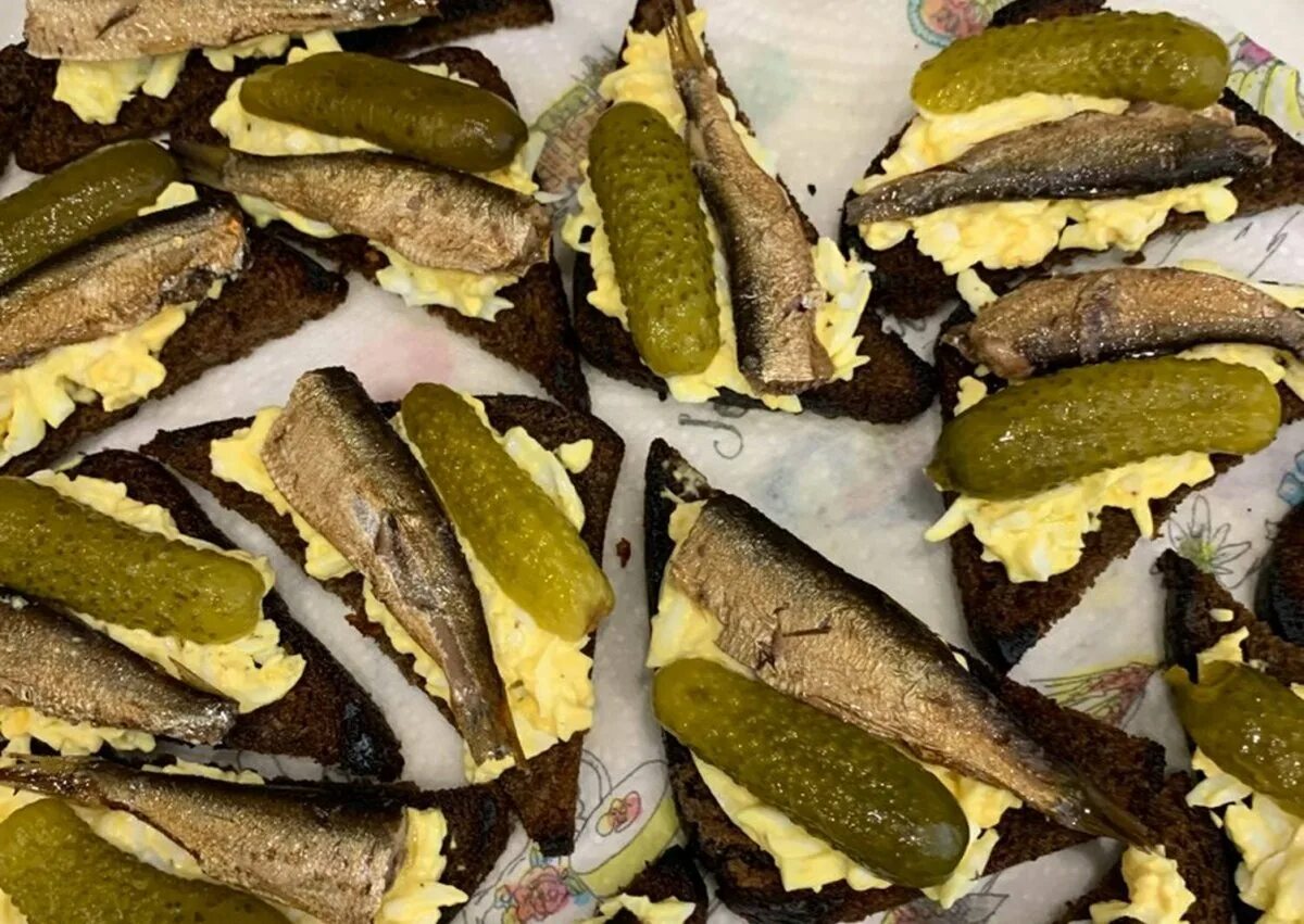 Бутерброд со шпротами и соленым. Бутер со шпротами и сол огурцом. бутерброды со шпротами и соленым огурцом на черном. гренки со шпротами. бутерброд шпроты с огурцом соленым.