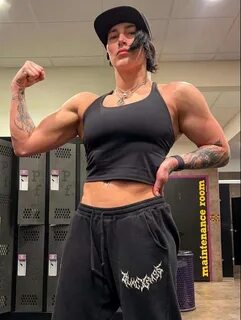 Rhea Ripley is wearing black shirt over trouser and cap or posing while tak...