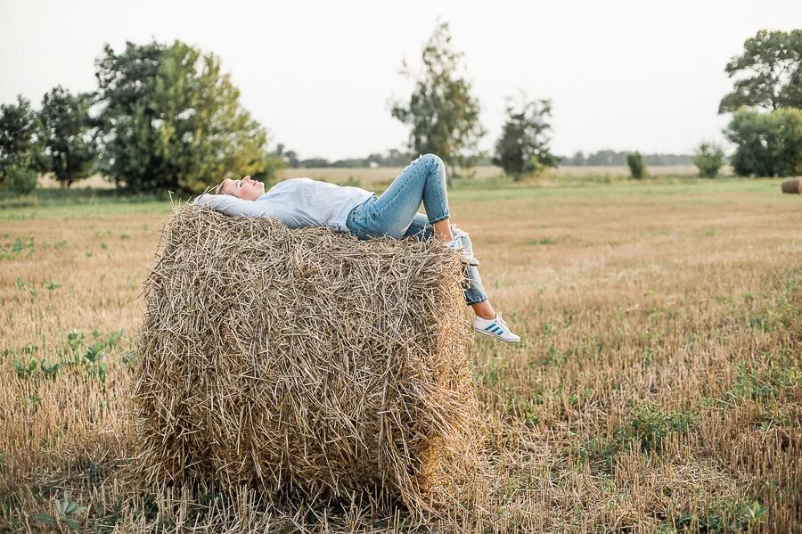 Девушка на сене. Девушка в соломе. Фотосессия с сеном. Сено в тюках на поле.