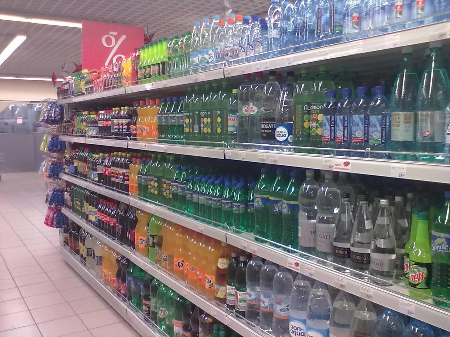 газированные напитки в магазине. выкладка напитков. витрина с продуктами. выкладка товара в магазине маленького. вертикальная выкладка товара в магазине.