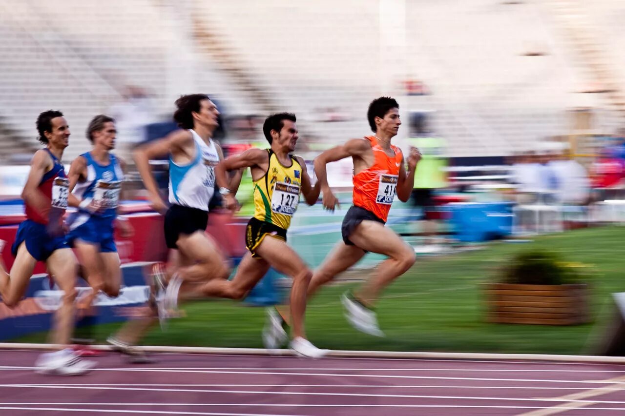 Спорт бег. Бегущий человек на стадионе. Бег соревнования мужчины. Комплексная эстафета бег.