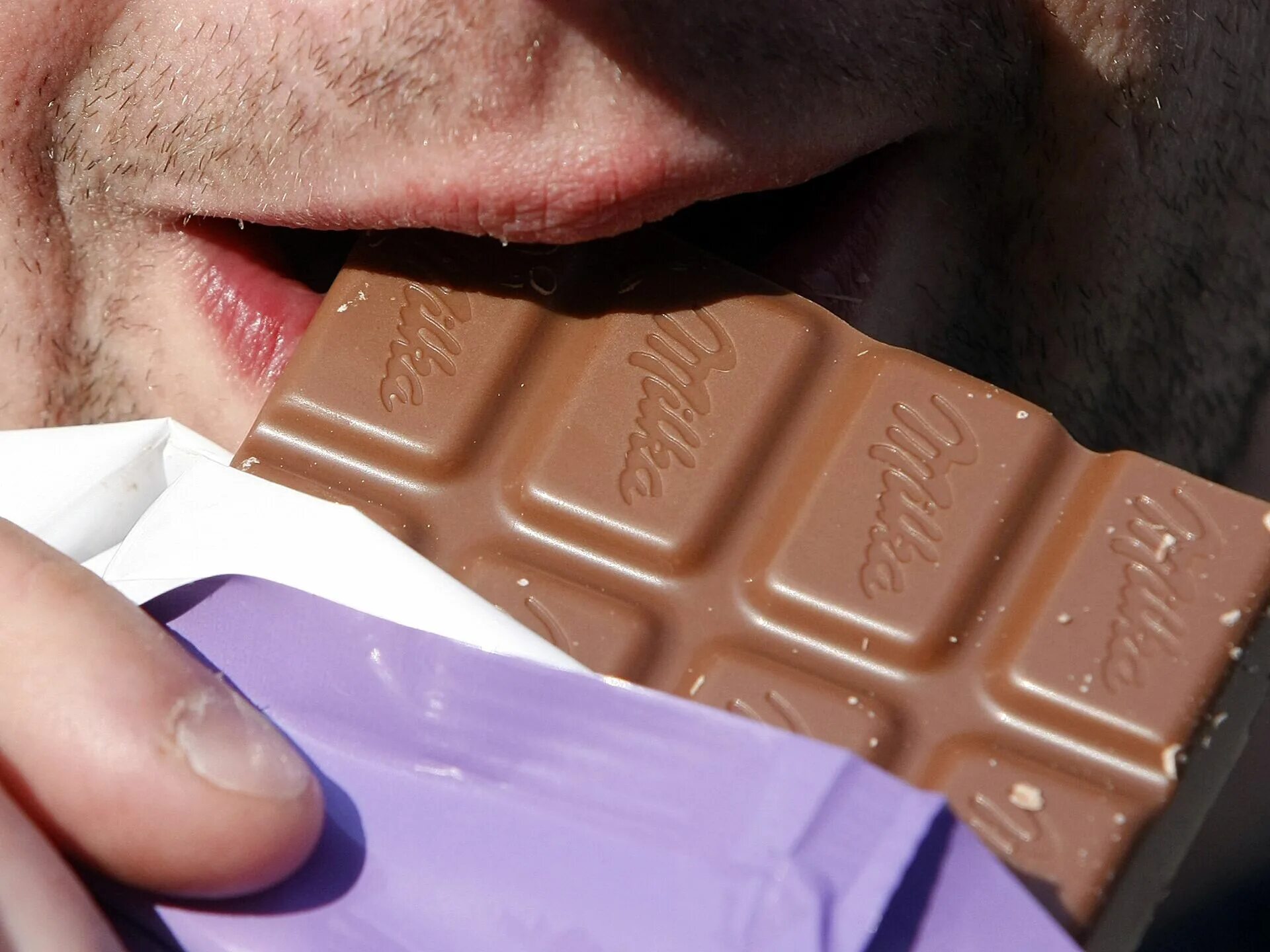 Шоколад подорожает. Мужчина ест шоколад. Парень с шоколадкой. Воровство шоколадок.