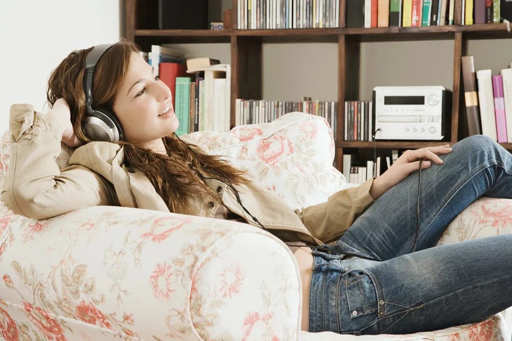 She listen to the radio. На диване с наушниками. Человек отдыхает дома с телефоном. Слушать музыку дома. Человек дома в наушниках на диване.