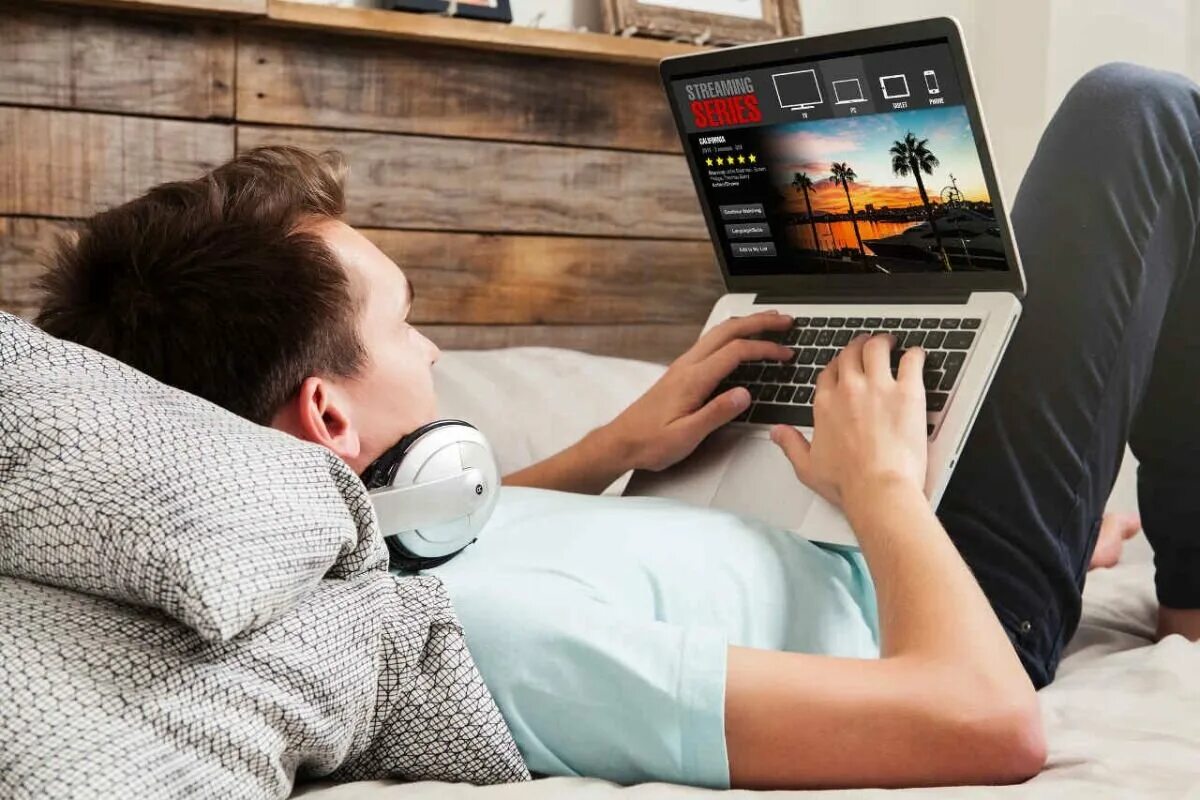 Играть с ноутбука с телефоном. Лежит с ноутбуком. Лежа за ноутбуком. Человек на кровати с ноутбуком. Лежит за компьютером.