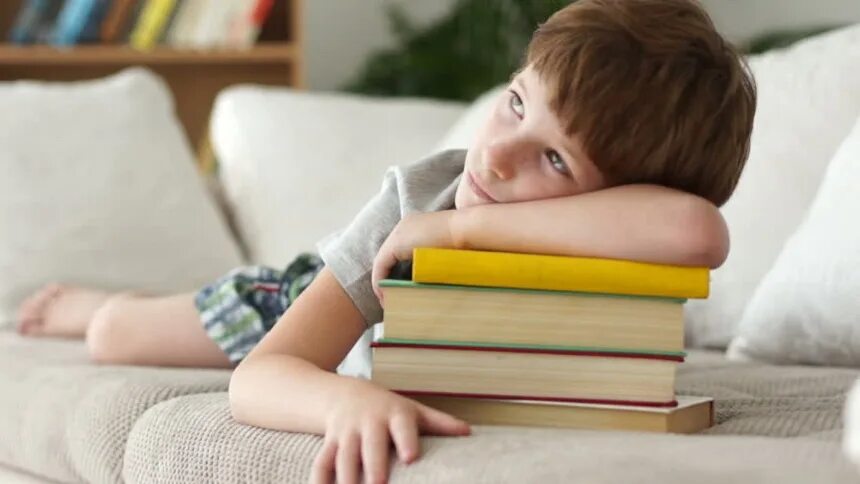 Уставший ребенок. Диван школьник. Мальчик лежит с книжкой. Мальчик закрывает книгу.