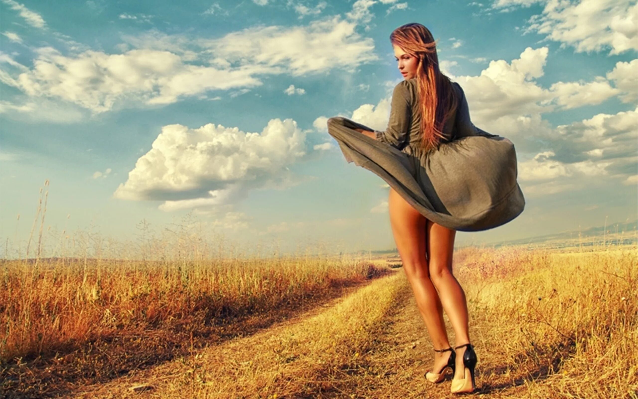 Девушка в платье на ветру. Фотосессия в поле. Юбка развевается на ветру. Девушка приподнимает плат.