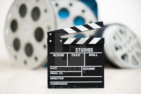 "Movie clapper board closeup with movie reels in background" stoc...