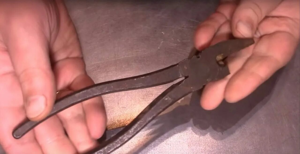 Зажатую плоскогубцами медную проволоку сгибают