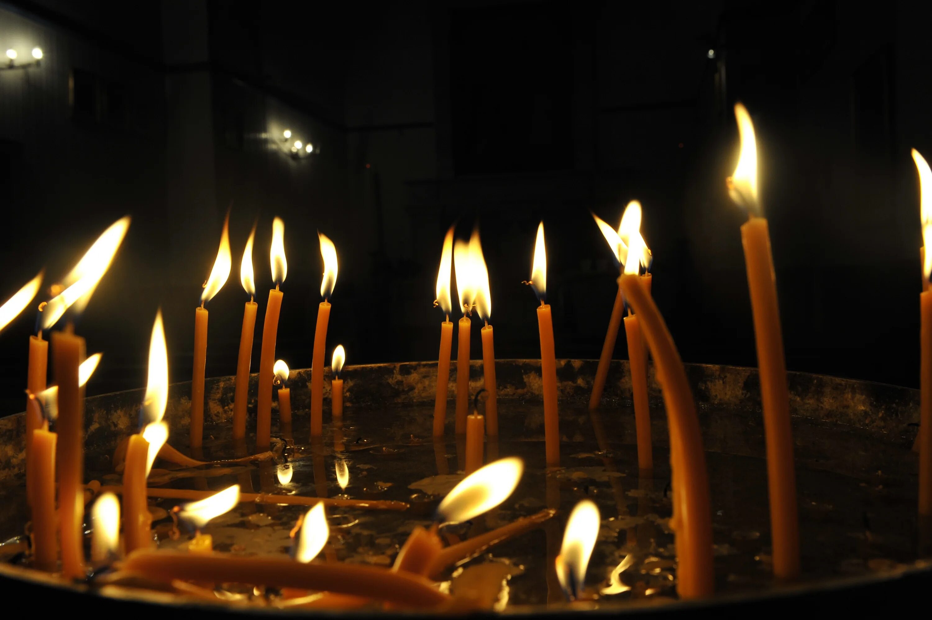 На столе стоит свеча которая отражается. Горящие свечи. Много свечей. Много горящих свечей. Огромная свеча.