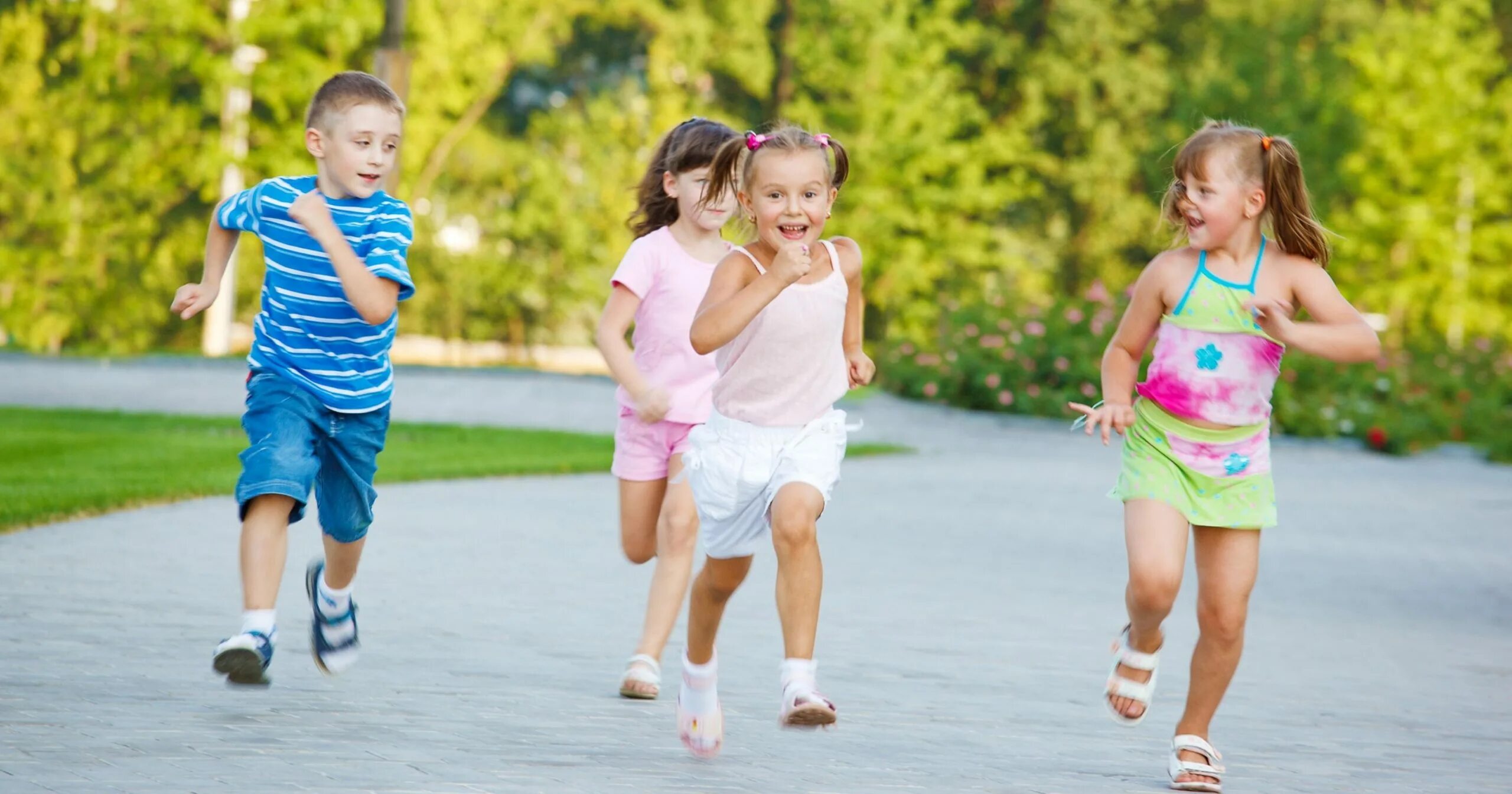 Детям летом кататься на улице. Дети бегают на площадке. Дети катаются на роликах. Летом катать ребёнка на прогулку.