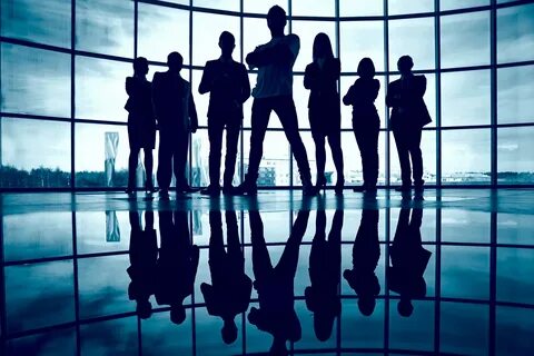 Business team standing against window with leader in front. 