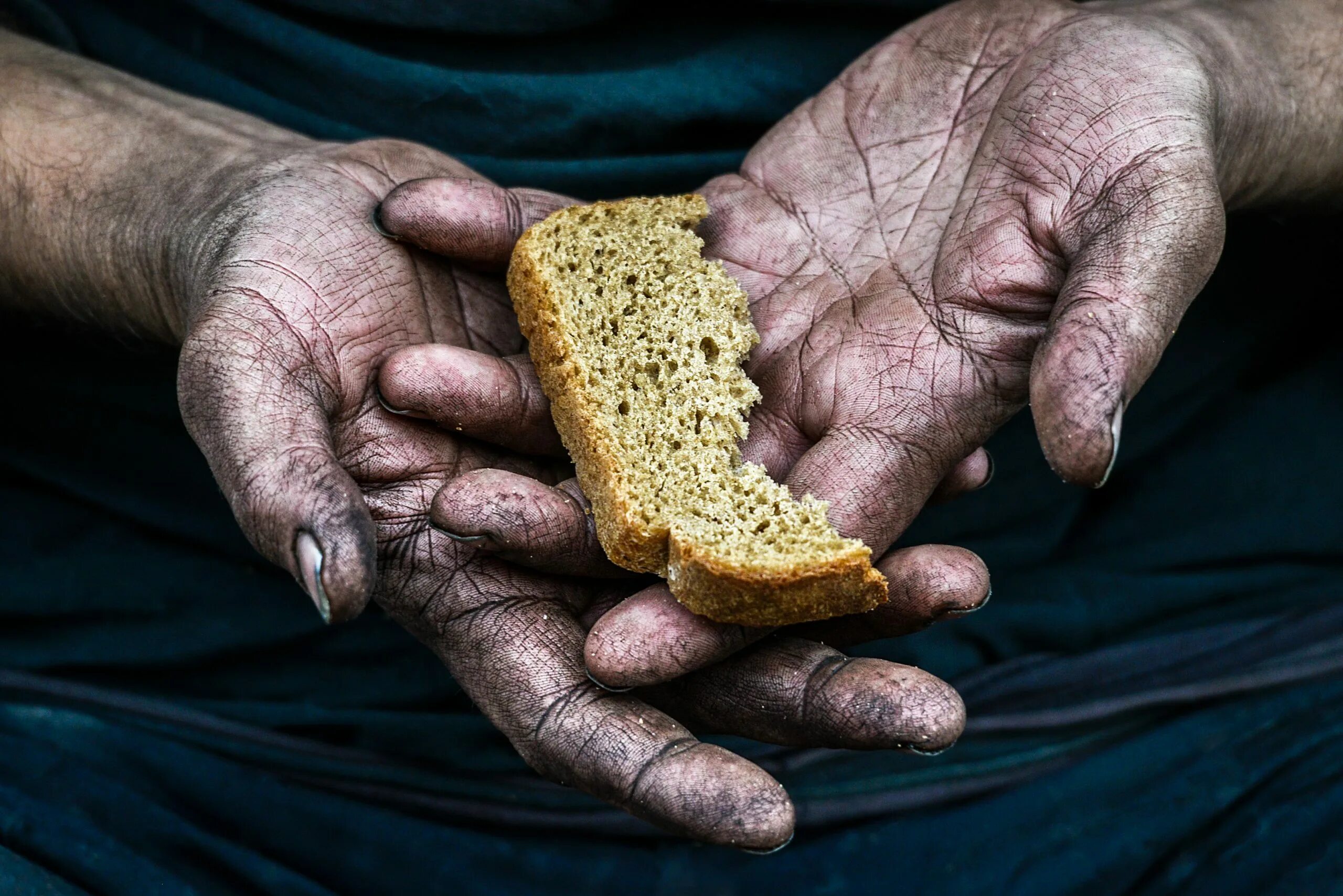 Голод и нищета. Кусок хлеба в руке. Хлеб в руках. Бедность хлеб.