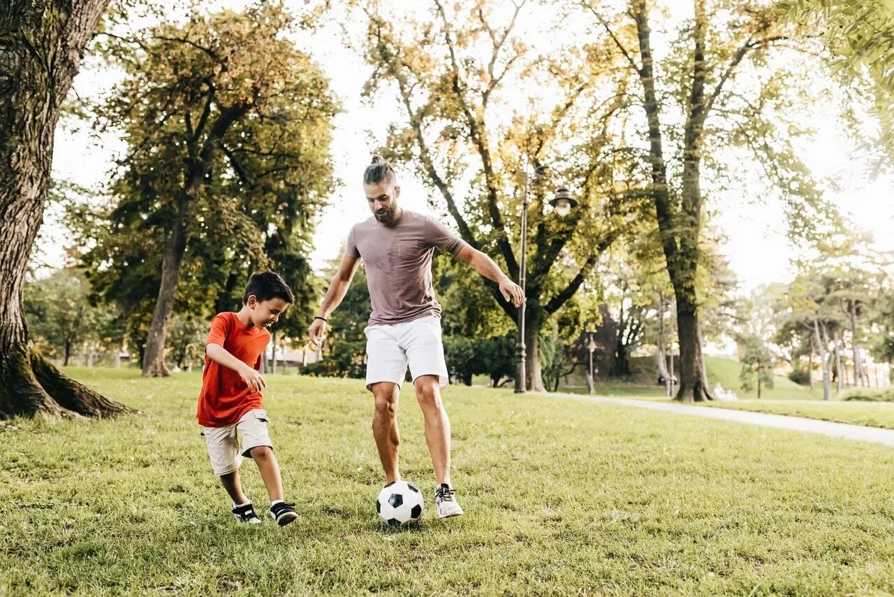 Семья играет в футбол. Папа играет с сыном. Папа учит сына играть в футбол. Папа с сыном играют в футбол. Научи папу играть
