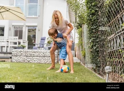 Mother playing with her son in a hammock in the garden Stock Photo. 