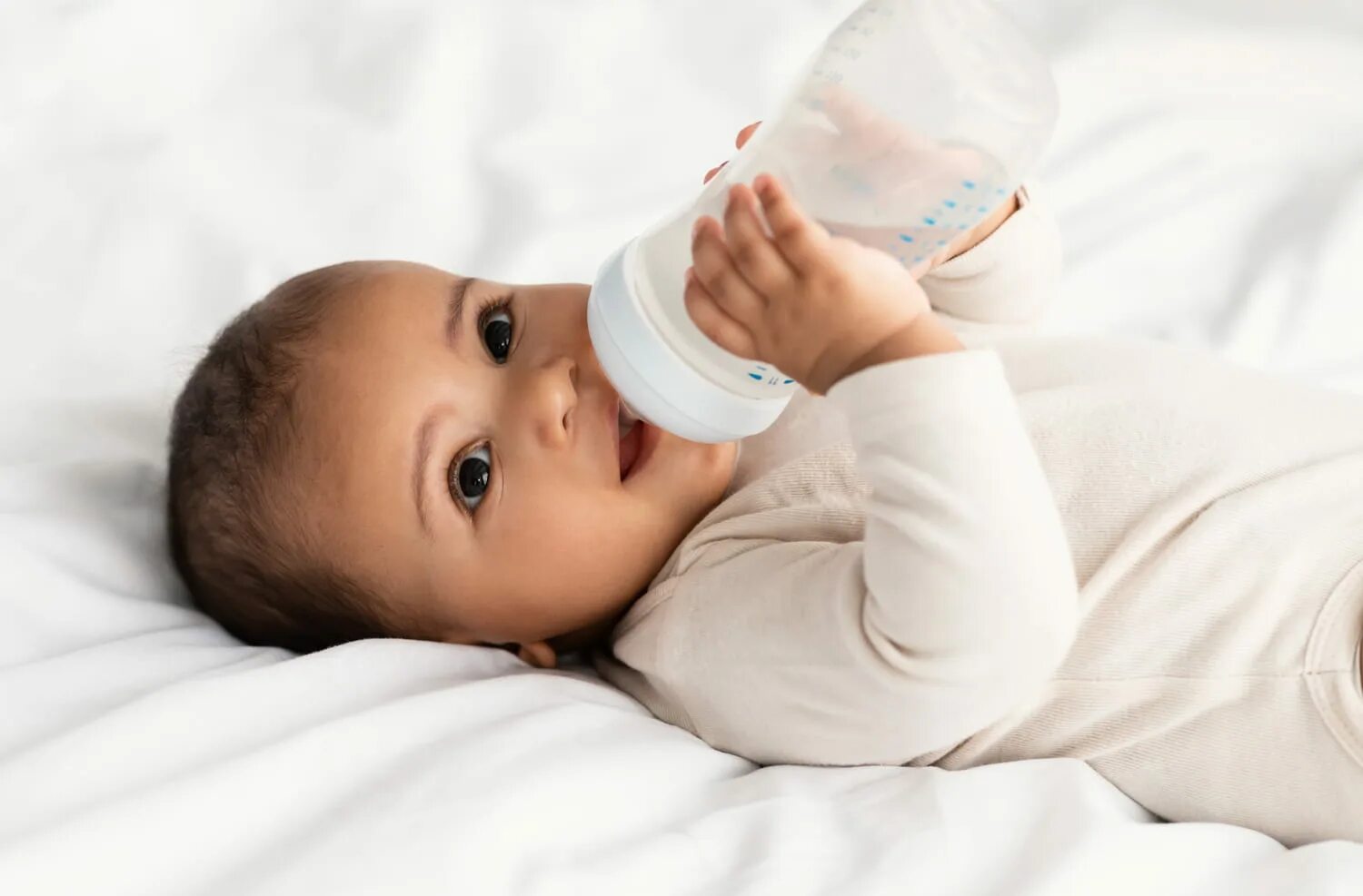 Малыш пьет из бутылочки. Малыш пьет из бутылочки в кроватке. Ребенок пьет из бутылочки лежа. Младенец пьет с бутылочки. Вода для новорожденных отзывы