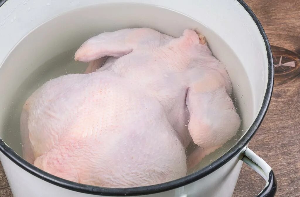Тушка курицы в кастрюле. Курица в воде.