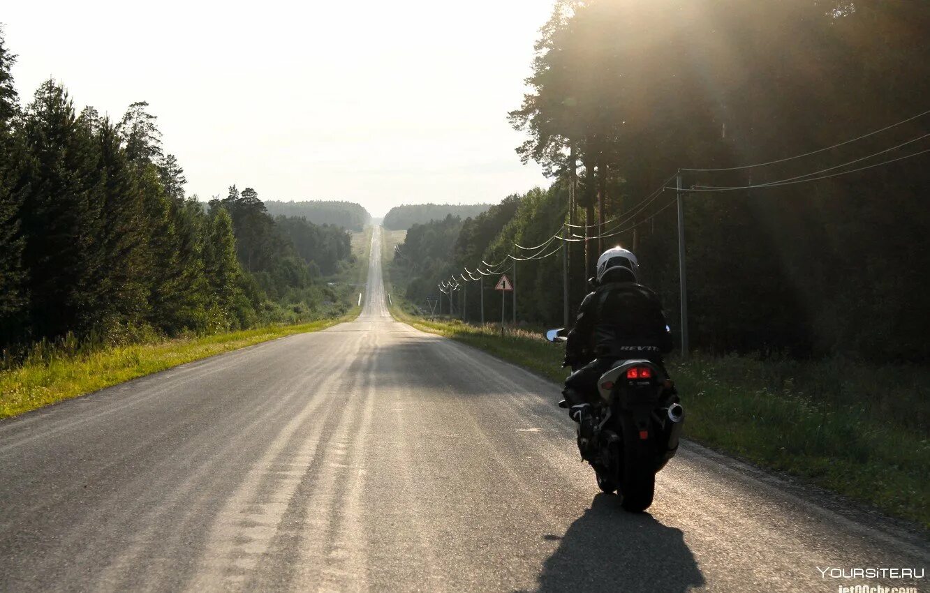 Легкая пыль несется по дороге далеко. Мотоцикл на дороге. Байкер на дороге. Мотоциклист на дороге. Мотоциклист на трассе.