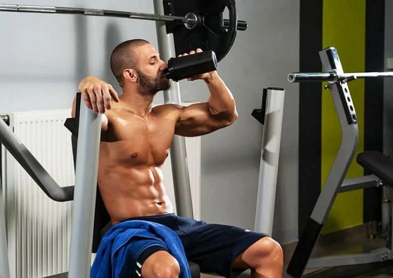 Вода в тренажерном зале. Спортсмен в спортзале. спортсмен с шейкером. худые мужчина в спортзале. вода в спортзале.
