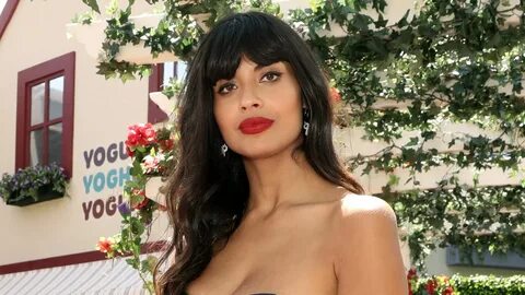 Jameela Jamil wearing red lipstick and a blue and white polka dot dress. 