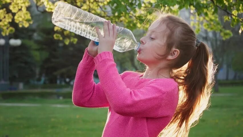 Дети пьют из бутылки. Девочка пьет воду. Ребенок пьет воду. Девушка пьет воду из бутылки. Девочка пьет воду в парке.