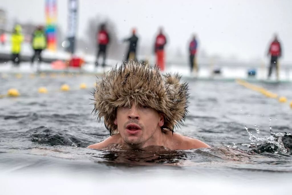 Плыть в холодной воде. Зимнее купание. Зимние купания в проруби. Купание в ледяной воде. Люди купаются.