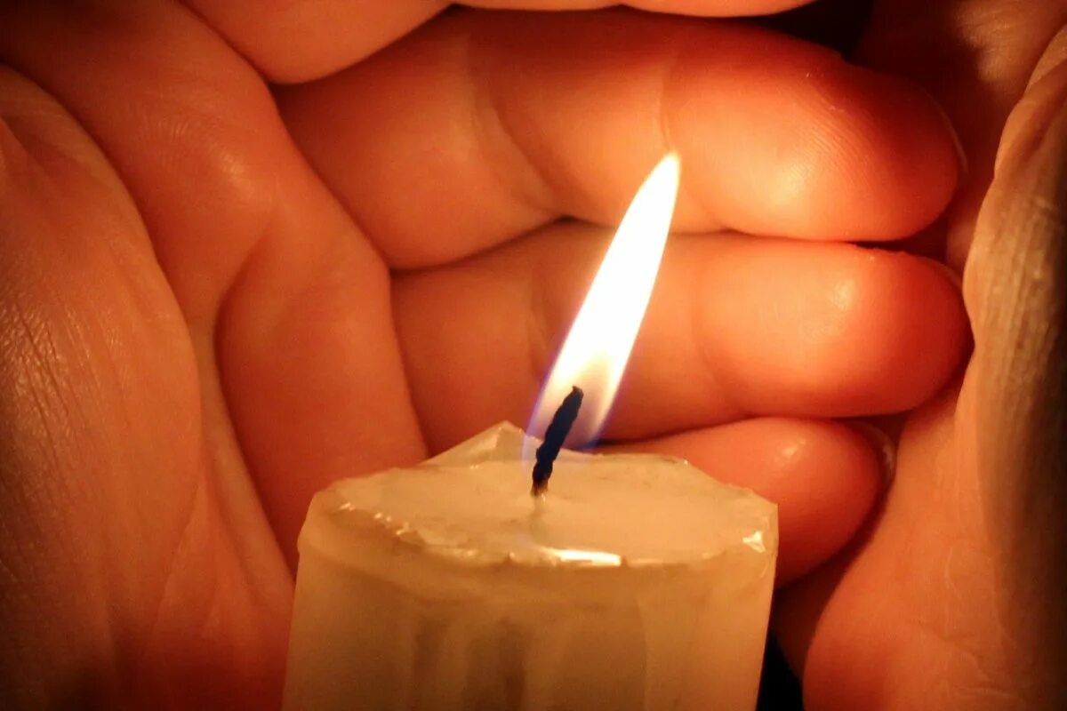 На столе стоит свеча которая отражается. Свеча. Свеча в руках. Зажженная свеча. Свеча памяти.