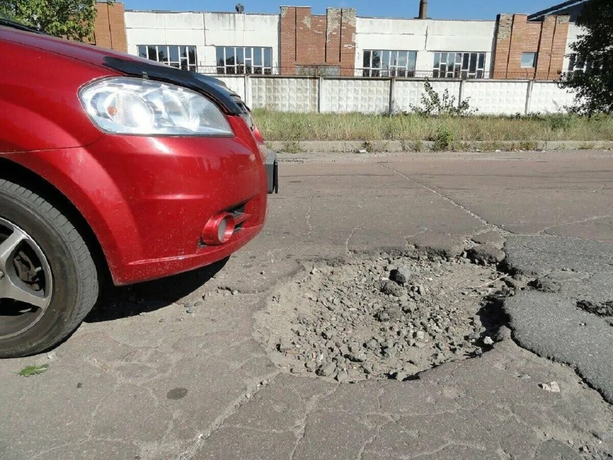 Колесо попало в яму на дороге. Ямы на дорогах. Ямы на дороге и автомобиль.