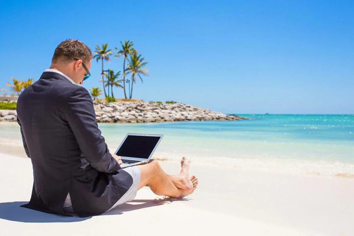 Бизнес удовольствие. Бизнесмен на море. Отпуск. Мужчина на берегу моря с ноутбуком. В костюме на пляже.