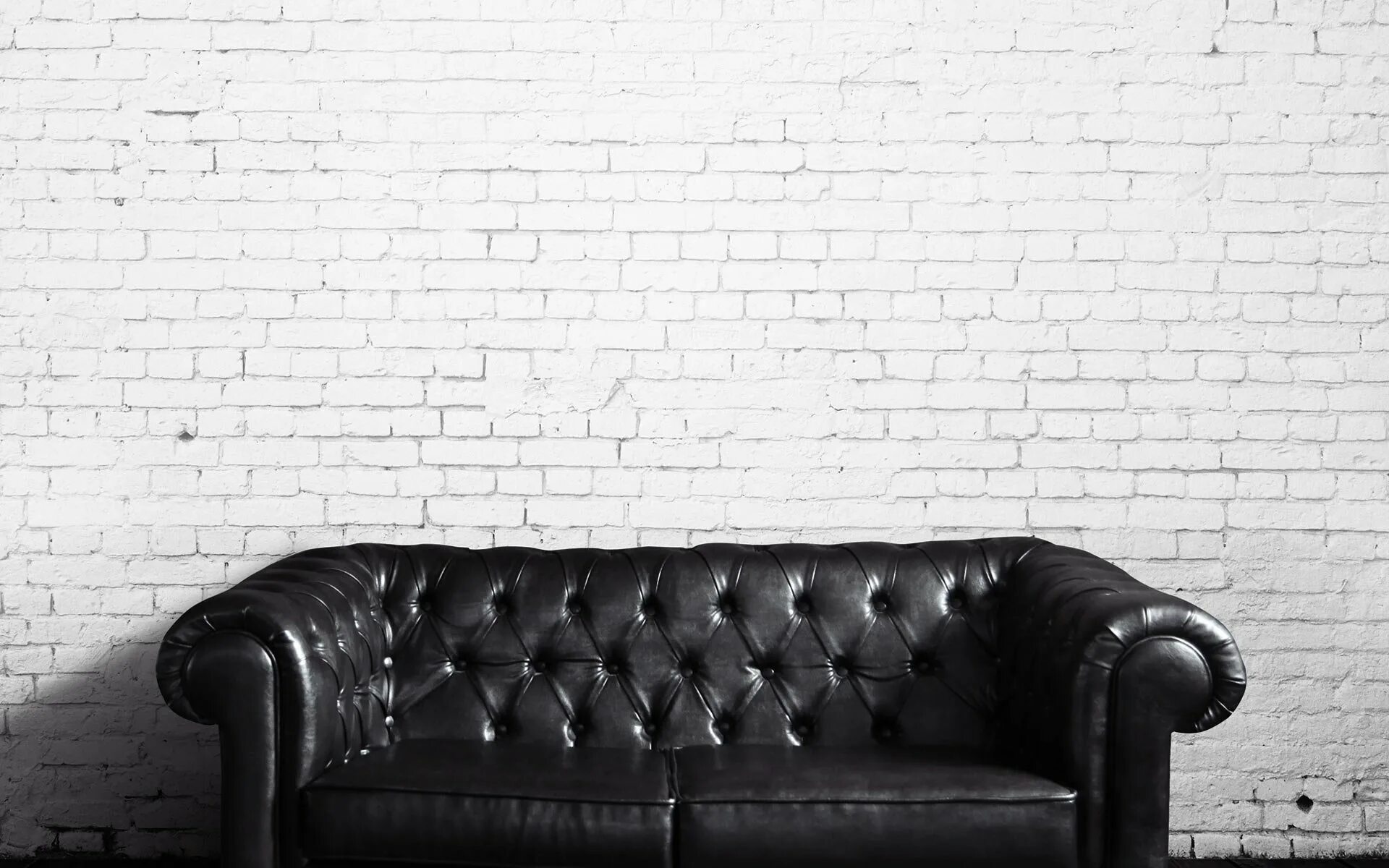 Возле черных белых стен. Кирпичная стена черно белая. Кирпичная стена кожаный диван. Белый кожаный диван в интерьере кирпича. Диван на фоне белой стены.