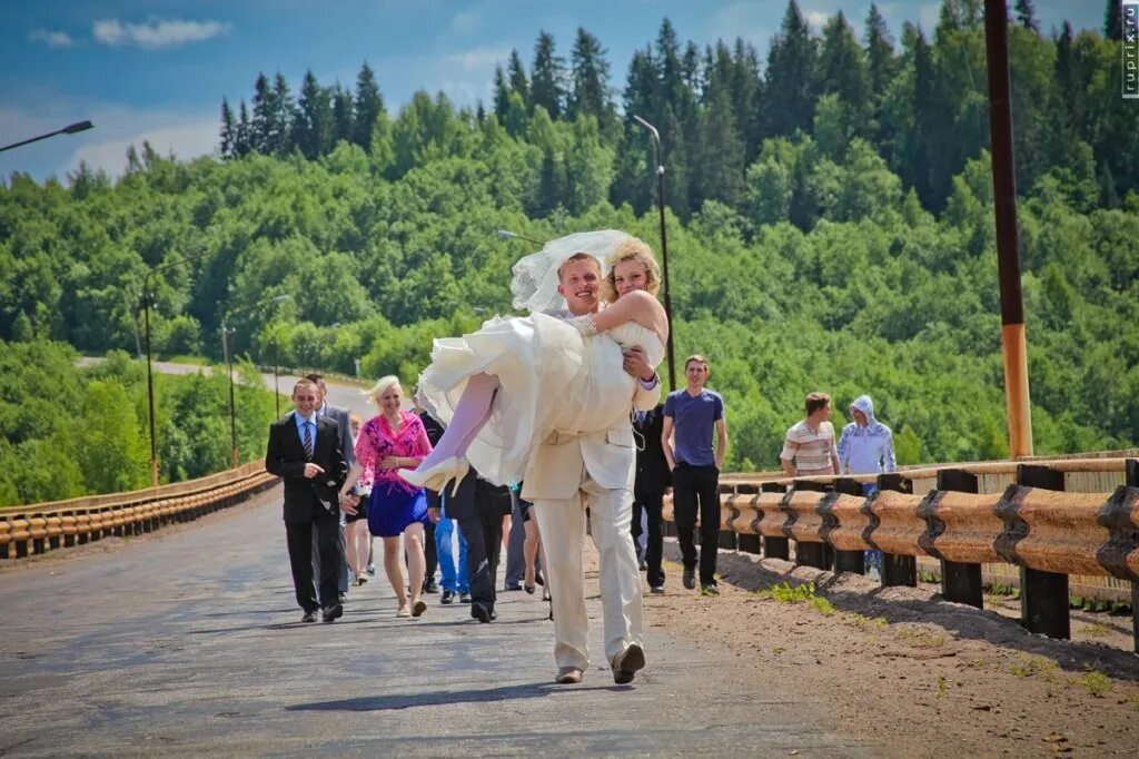 Невесту через мост. Жених несет невесту через мост. Жених несет невесту на руках через мост. Молодожены на мосту. Несет жениха