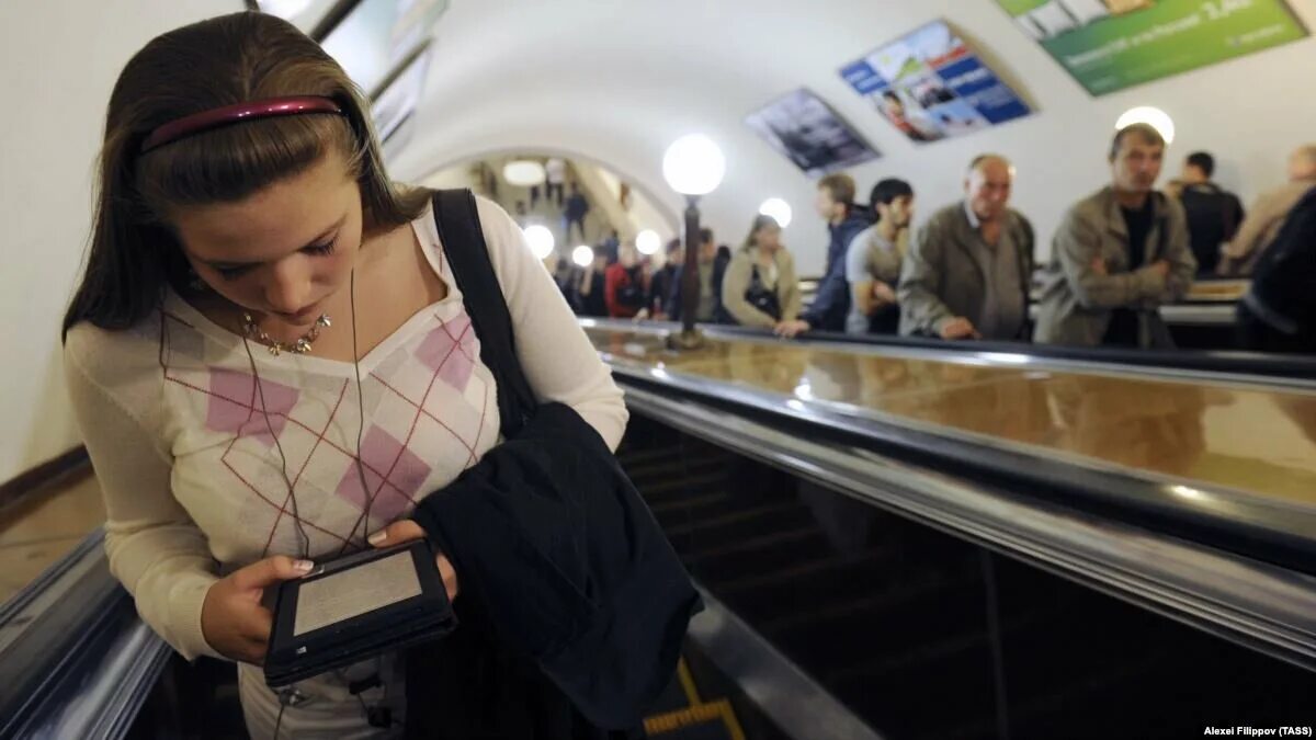 Читают в метро. Чтение электронной в транспорте. Люди читают в метро. Телефон в метро. Она читает в метро