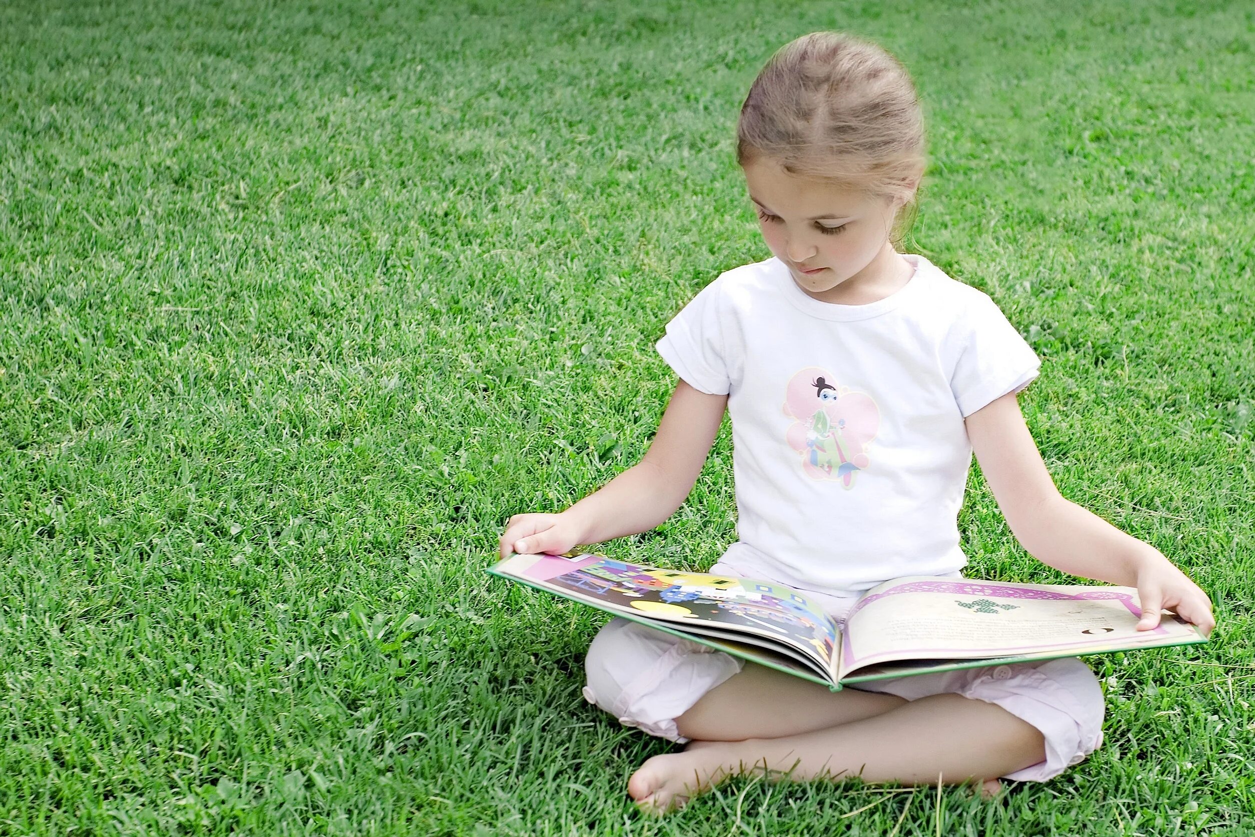 Large in little. Дети читают. Девочка сидит на траве. Чтение на лужайке. Мальчик на лужайке.