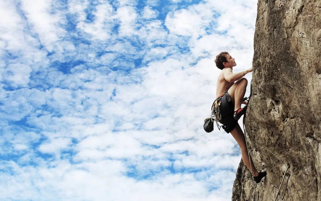 Карабкаться вверх. Человек на скале. Карабкаться вверх. Турист скалолаз. Человек лезет в гору.