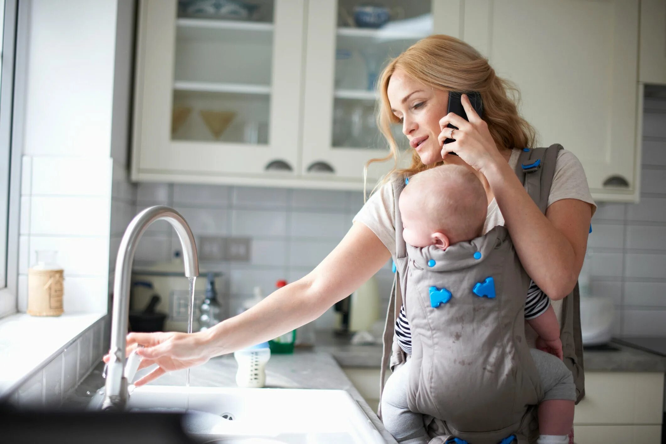 While mom. A woman holding a baby and making a baby. ec hold baby. holding babysitting. mom does house works.
