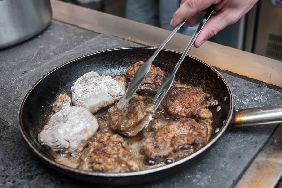 Жареный бобер на сковороде. Обжаривание мяса горелкой. Жареное мясо с тестом на сковороде