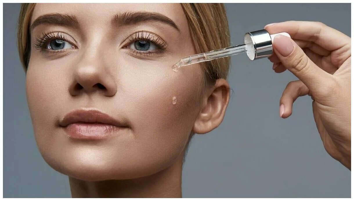 девушка с сывороткой. наносим сыворотку на лицо. девушка сыворотка для лица. использование сыворотки для лица. нанесение сыворотки на лицо.