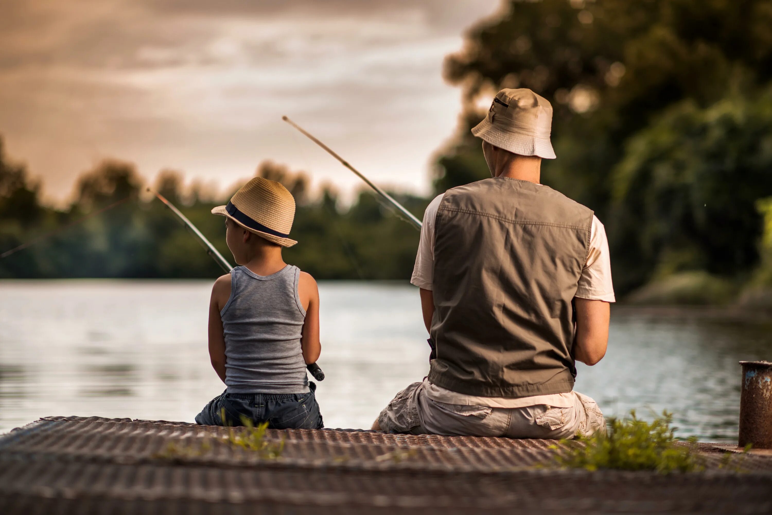 Отец и сын на рыбалке. Папа и сын рыбачат. Рыбак сидит спиной. Рыбак фотосессия.