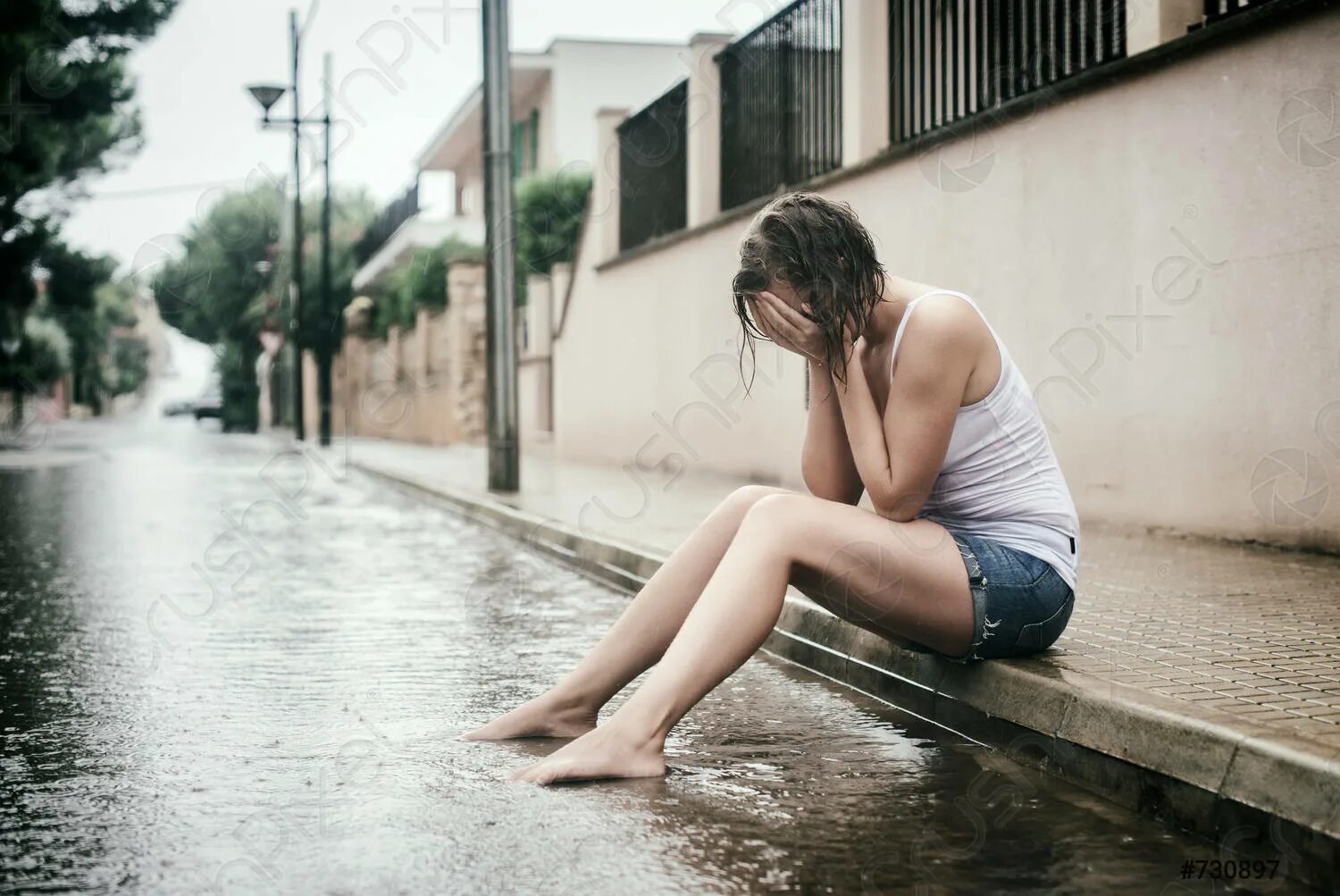 Девушка сидит под дождем. Женщина плачет на улице. Плачет под дождем. Печальная женщина.