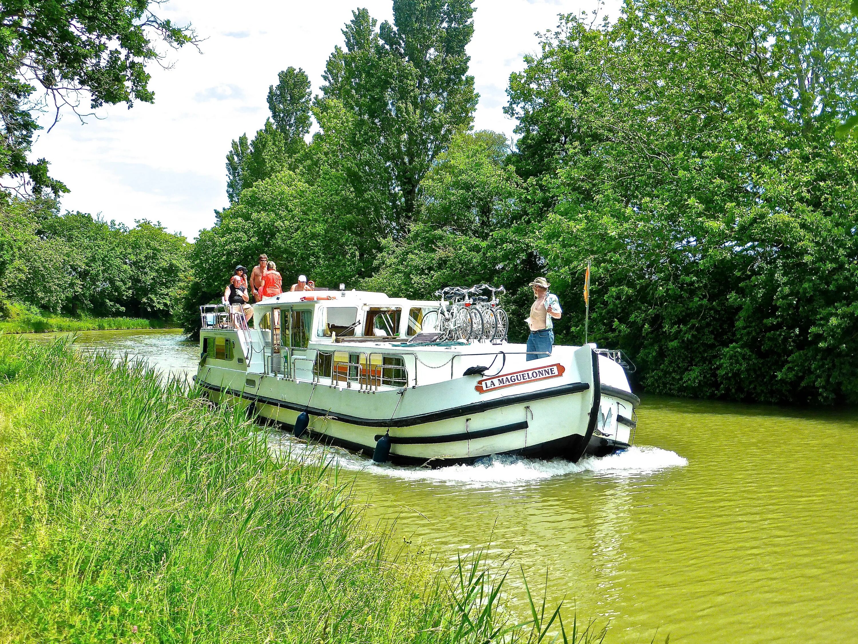 Рассекая воду плывет по реке катер впр. Речные лодки "River Boats". Катер для путешествий по реке. Катер для туризма.